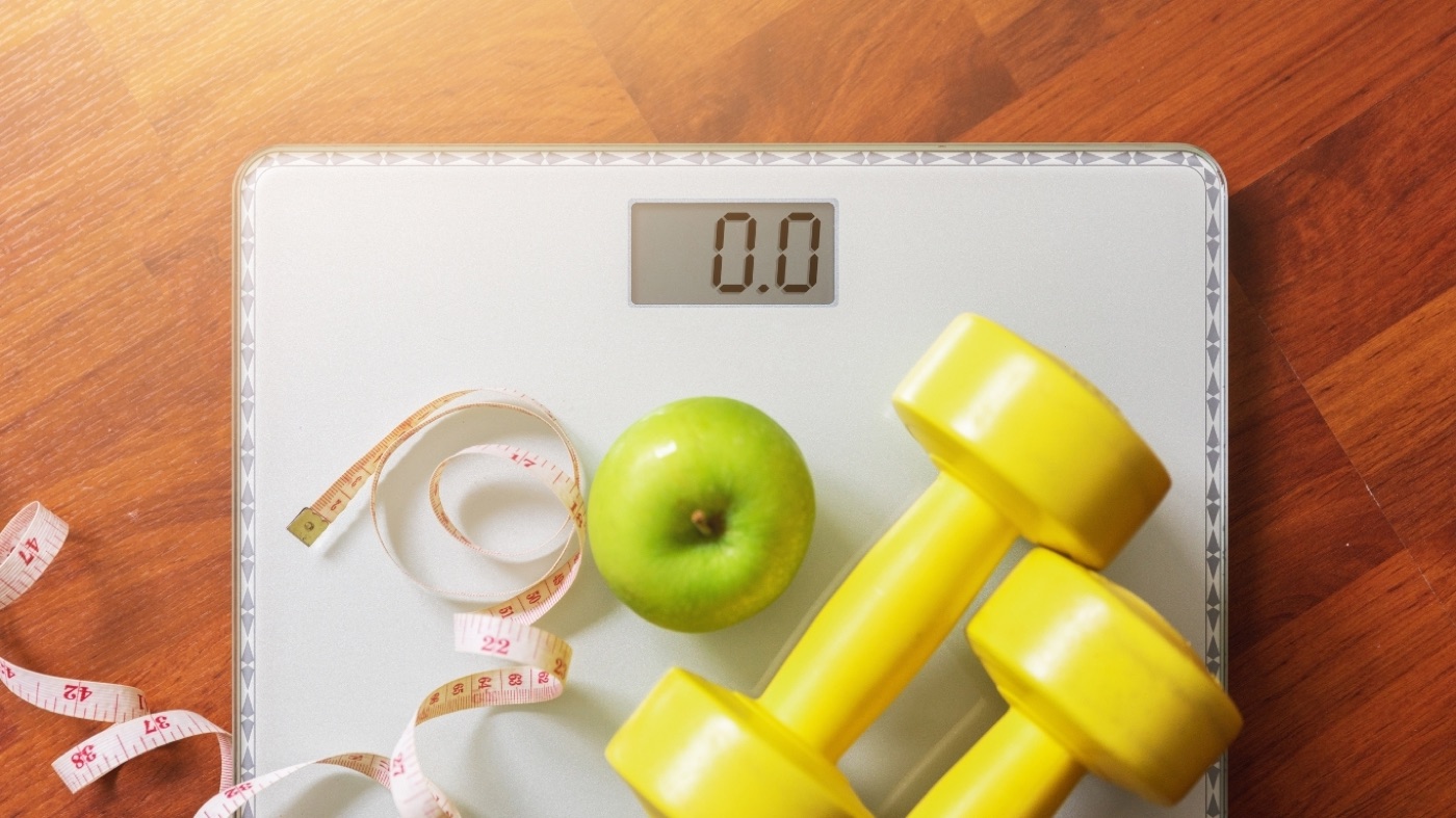 Scale with dumbbells and apple representing GLP-1 metabolic health for women over 40